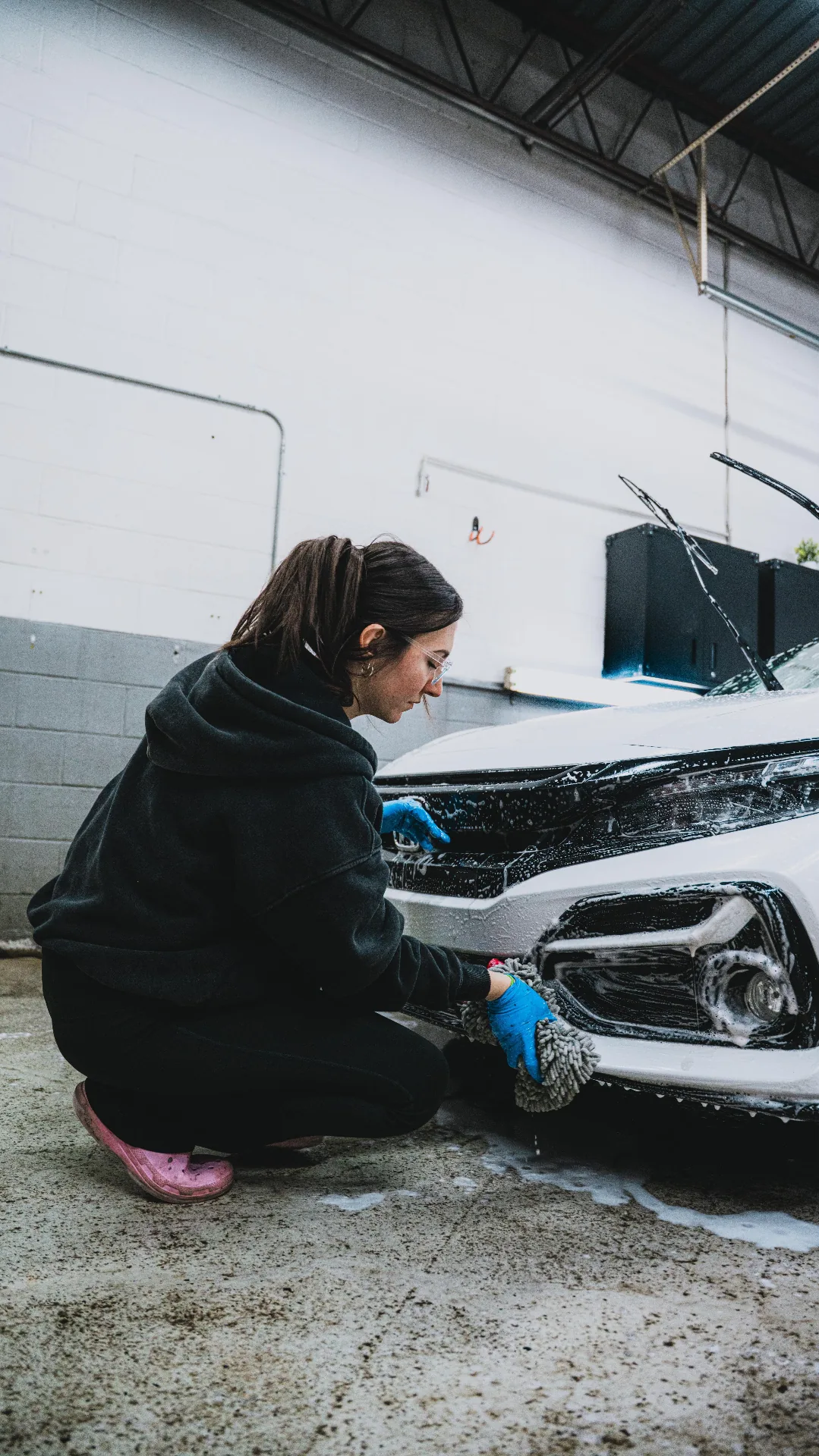 Owner hand foam washing the front of a white sedan